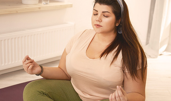 Woman sitting on the floor of her home doing the meditation.