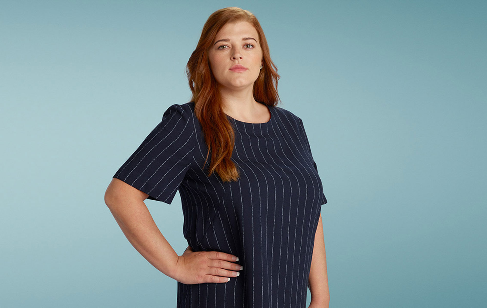 Frau steht seitlich und blickt in die Kamera